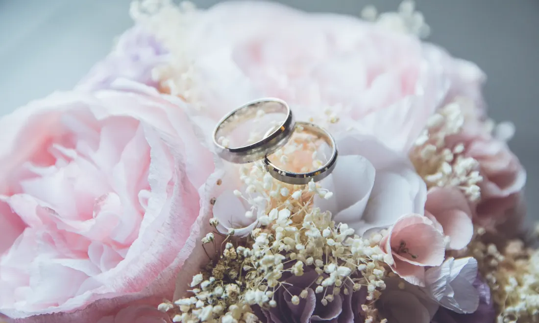 Wedding rings resting on soft florals — a detail study from a design direction reference